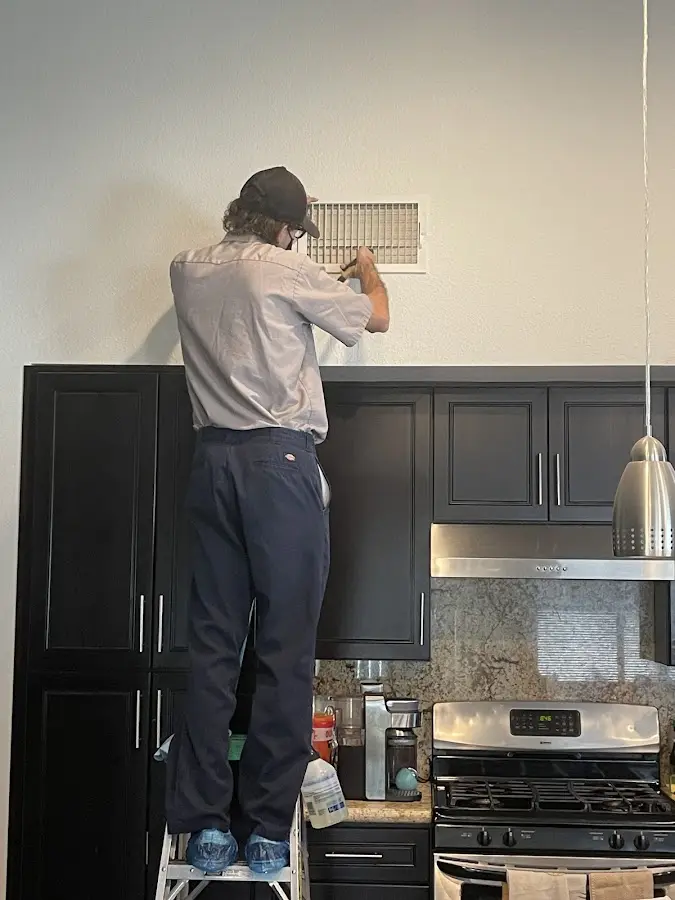 Technician inspecting an air vent during HVAC service in Hickory Hills